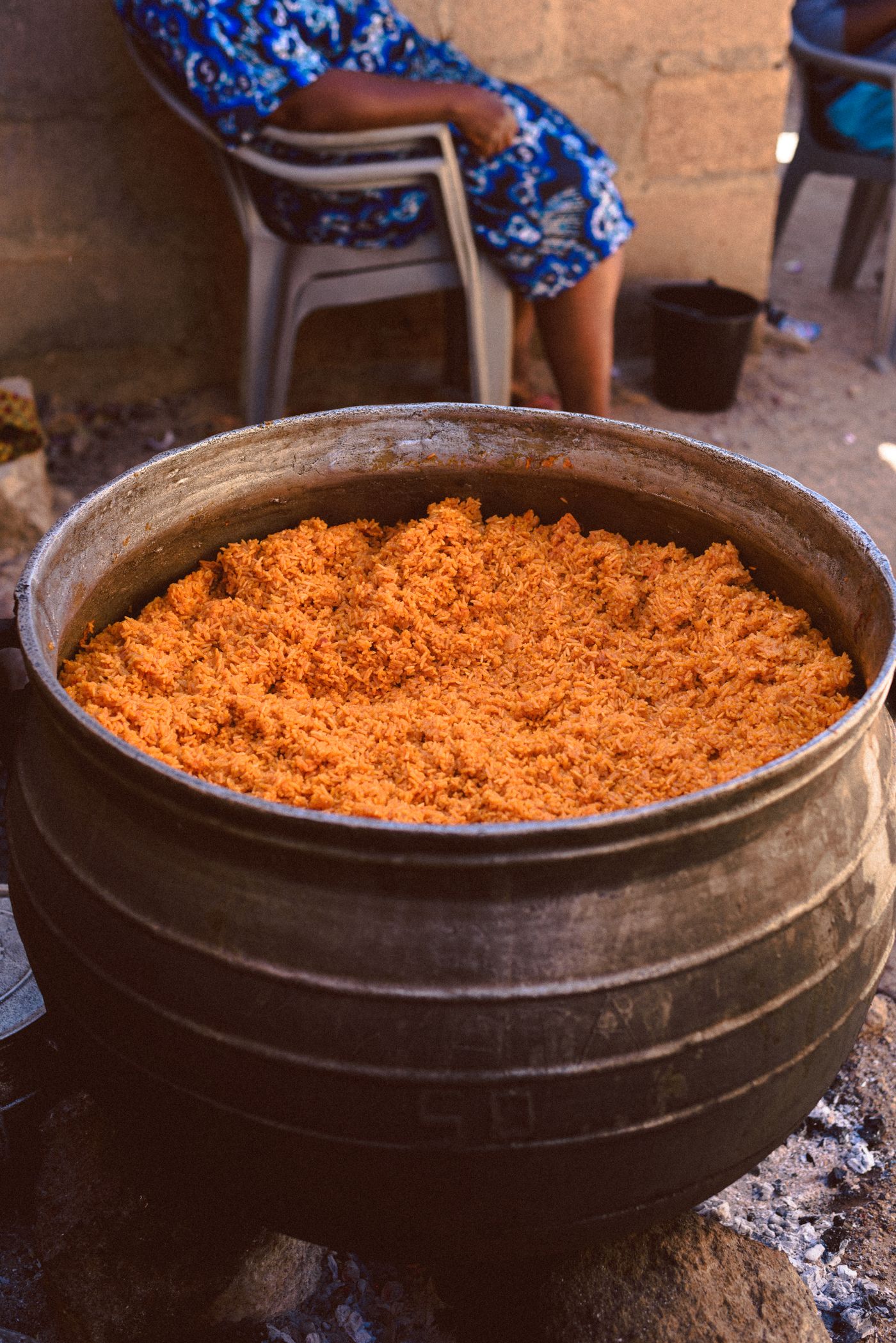 A large pot of party jollof rice cooking over firewood